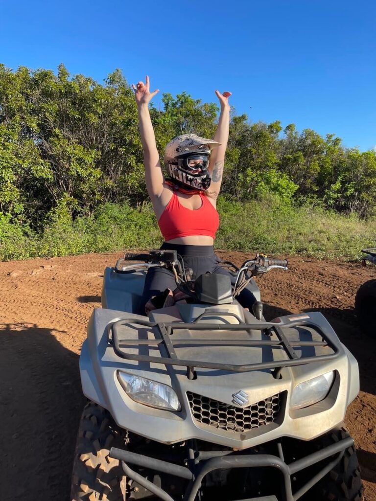 Image of a woman with her hands up as she sits on an ATV in Hawaii