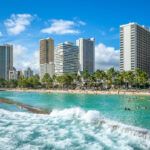 Find out the best things to do in Honolulu Hawaii recommended by top Hawaii blog Hawaii Travel Spot! Image of Waikiki Beach from the water with Honolulu in the background