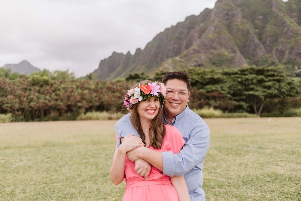 Image of a man and woman embracing at Kualoa Beach Park with mountains in the background