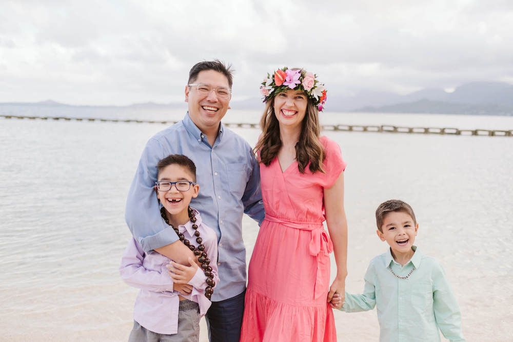 Image of a family of four in pastel rainbow colors in front of the ocean