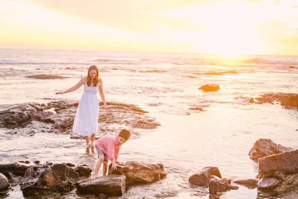 Image of a mom wearing a white dress and a boy wearing a red shirt walking around the tidepools in Kona Hawaii