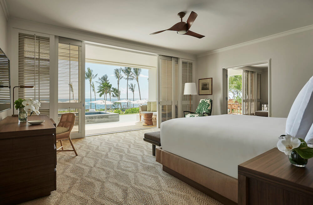Image of the inside of a clean hotel room overlooking the ocean and palm trees at the Four Seasons Ko Olina