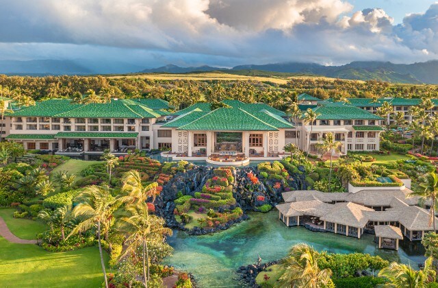 Image of a sprawling hotel with lush gardens and palm trees surrounding it at the Grand Hyatt Kauai