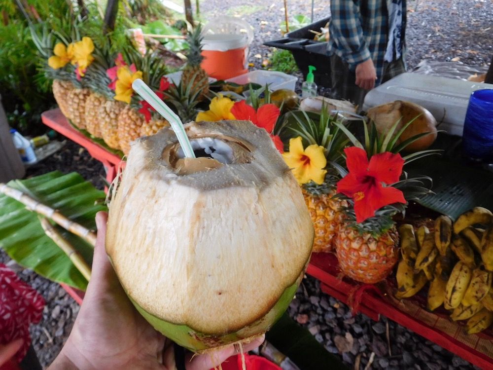 Image of a fresh coconut drink with pineapples in the background at the Hilo Farmers Market