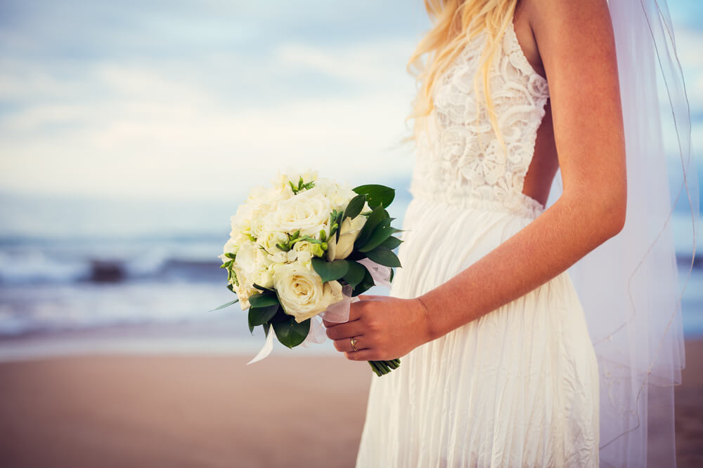Image of a bride holding a bouquet on a beach in Hawaii