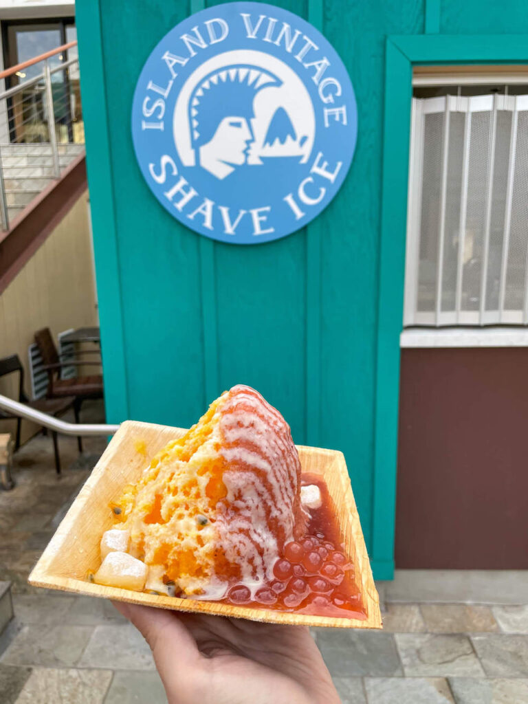 Image of a square bowl with shave ice in front of the Island Vintage Shave Ice sign on Maui