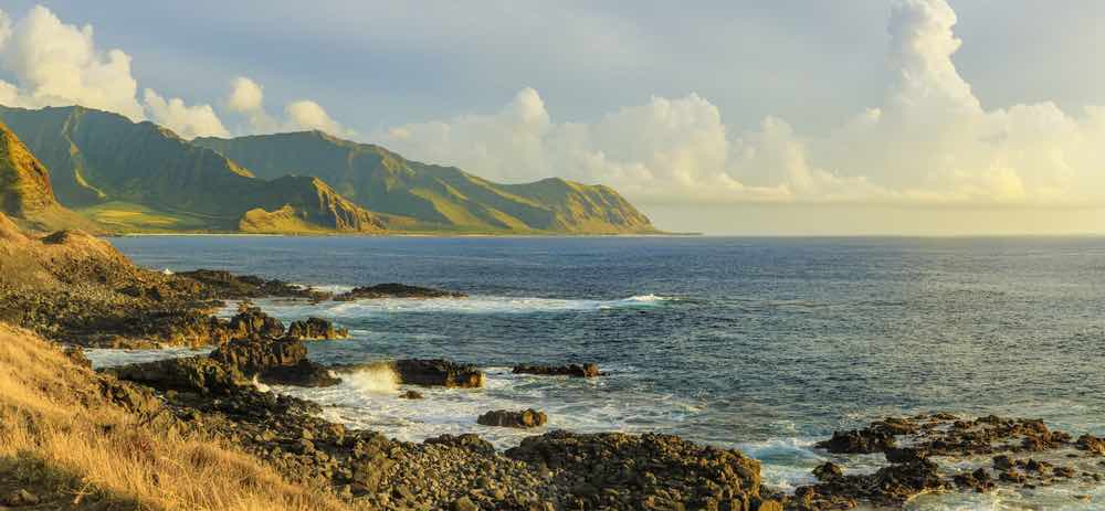 Image of a rugged coastline with mountains in the background at golden hour