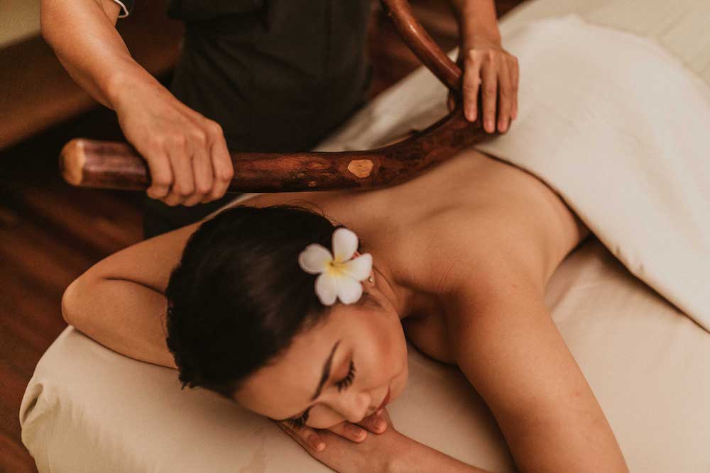 Image of a woman with a flower in her hair getting a massage at the Photo credit: Kahala Hotel & Resort