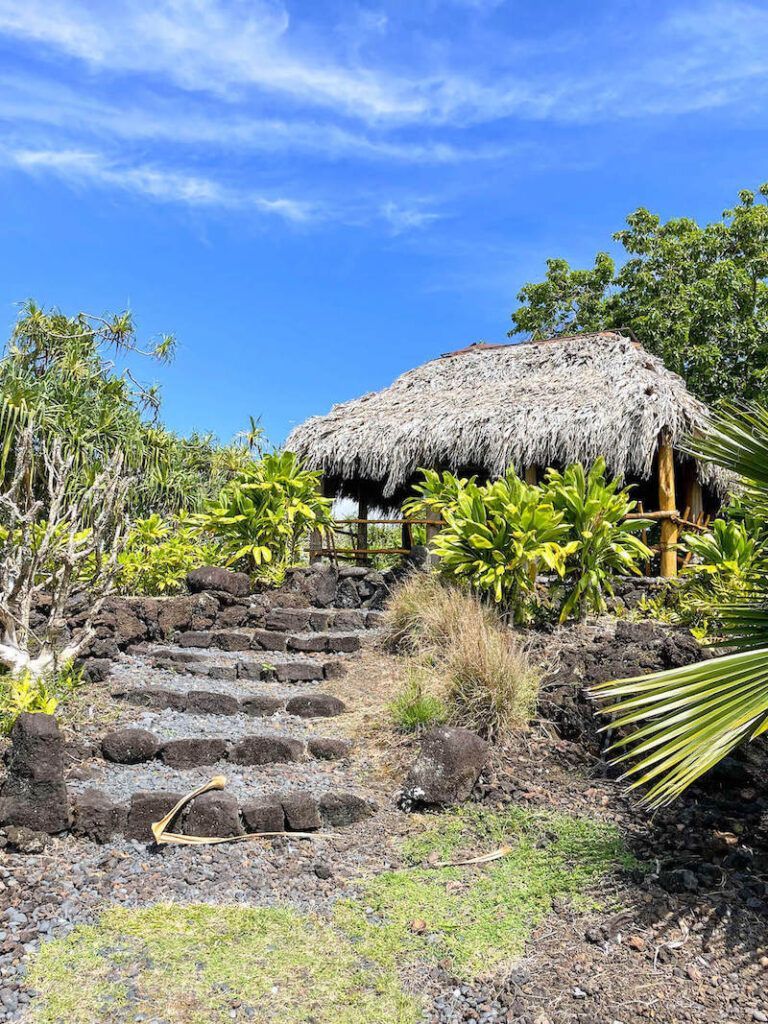 Image of a grass hut with rock stairs leading up to it at a Hana Maui garden