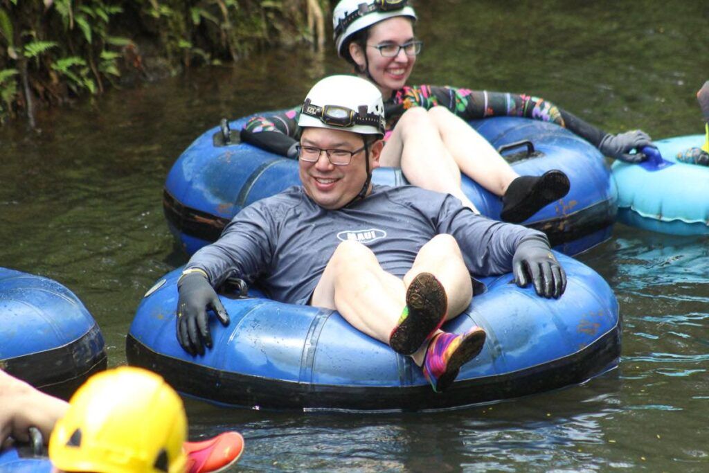 Image of a man and woman lounging in inner tubes floating down a Kauai river