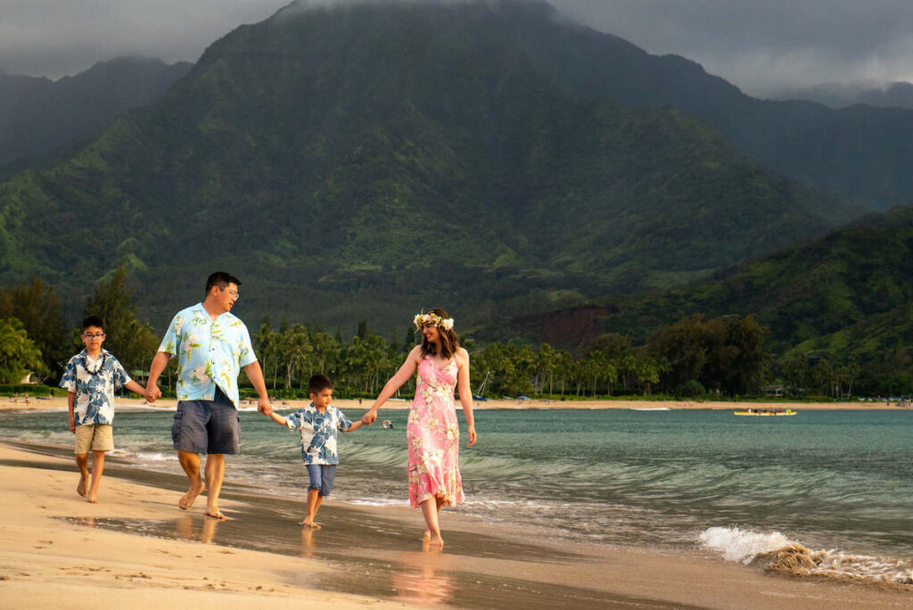 Image of a family of four walking down the beach on Kauai wearing Hawaiian print clothing