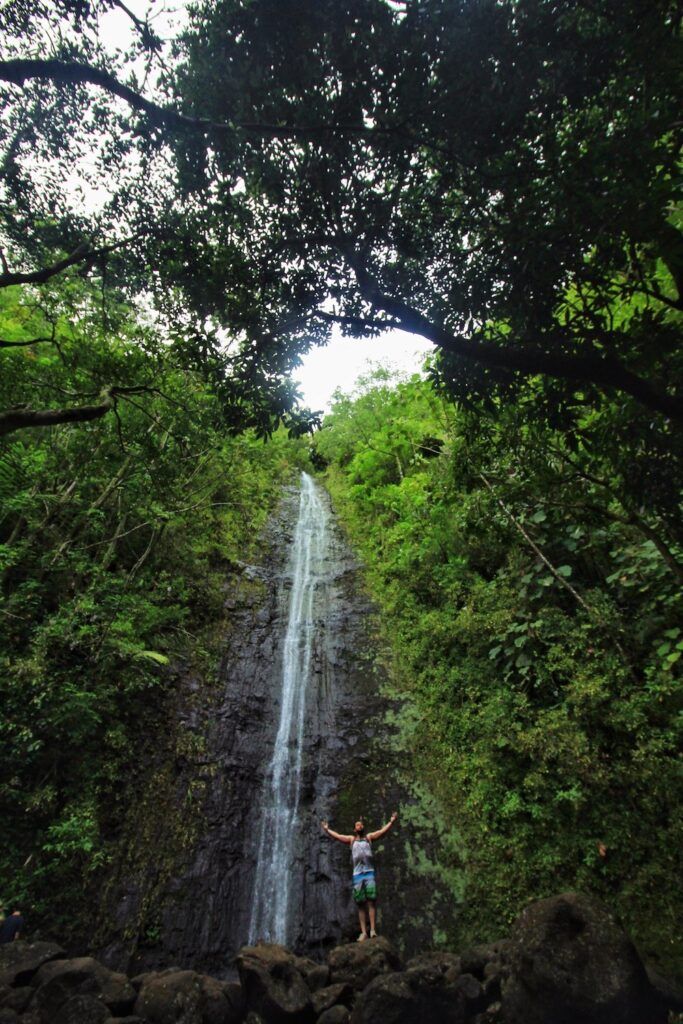 Image of a man wth outstretched arms standing in front of Manoa Falls on Oahu