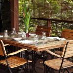 Find out the most romantic Oahu restaurants recommended by top Hawaii blog Hawaii Travel Spot! Image of a wooden table with a tropical background