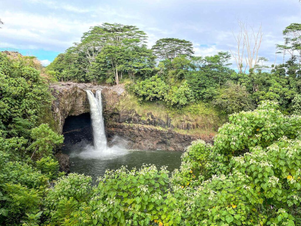 Image of a short waterfall surrounded by lush greenery. Rainbow Falls on the Big Island of Hawaii