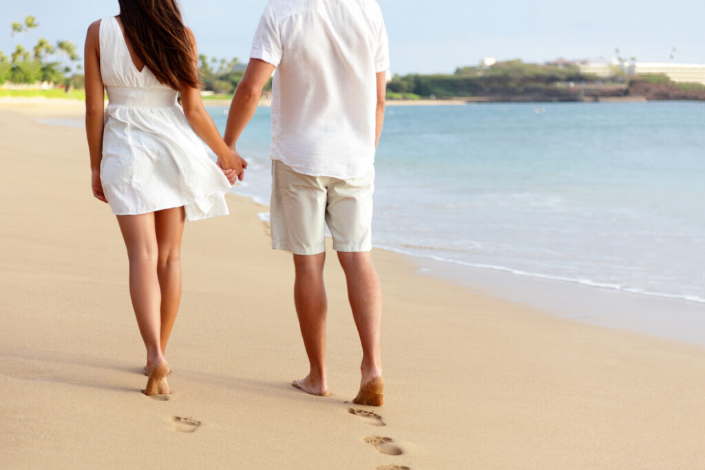 Image of a man and woman walking on the beach away from the camera