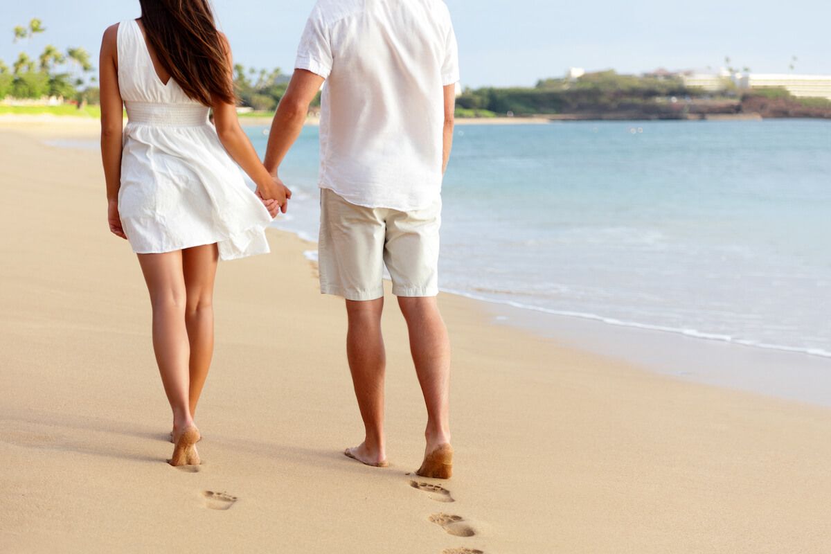 Find out the most romantic honeymoon activities in Maui recommended by top Hawaii blog Hawaii Travel Spot! Image of a man and woman walking on the beach away from the camera