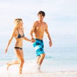 Find out the most romantic things to do on the Big Island of Hawaii recommended by top Hawaii blog Hawaii Travel Spot! Image of a man and woman holding hands in the ocean while wearing swimsuits