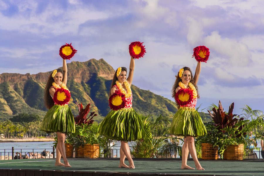 Image of three hula dancers on a stage with Diamond Head in the background