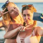 Find out the cutest summer beach quotes for Instagram by top Hawaii blog Hawaii Travel Spot! Image of two girls in bikinis taking a beach selfie