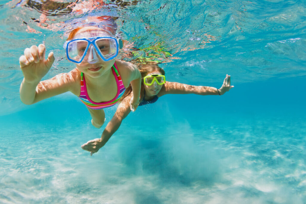 Find out the best things to do on the Big Island with family recommended by top Hawaii blog Hawaii Travel Spot! Image of a kid and mom snorkeling in clear water