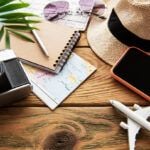 Find out the best tips for visiting Hawaii for the first time by top Hawaii blog Hawaii Travel Spot! Image of a hat, phone, laptop, camera, mini airplane and sunglasses on a flat lay of travel planning