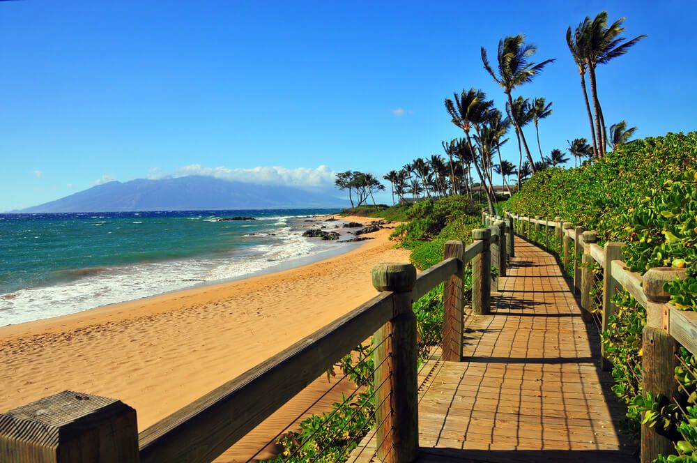 Image of a wooden boardwalk next to a golden sandy beach in Wailea Maui