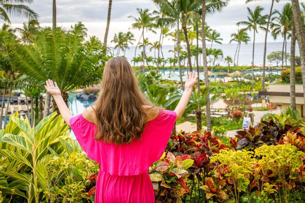 Image of a woman wearing a pink dress looking out at the lush tropical garden at the Grand Hyatt Kauai