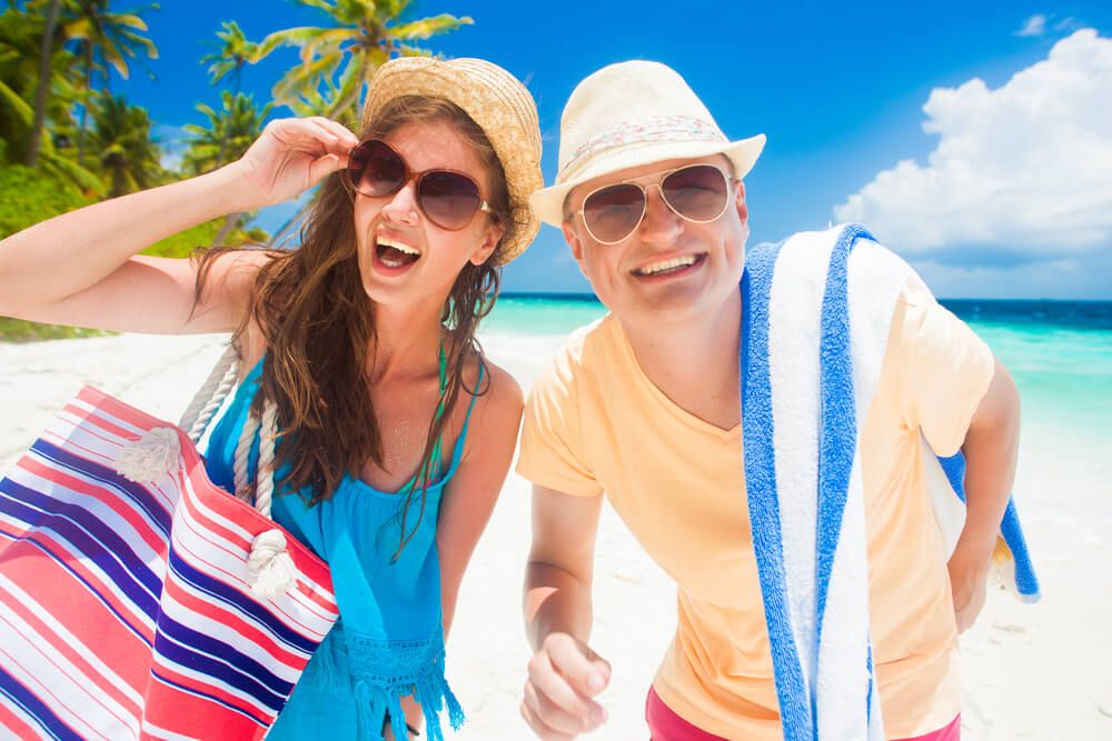 Find out what to wear in Hawaii suggested by top Hawaii blog Hawaii Travel Spot. Image of a man and woman wearing beach clothes in front of a tropical background