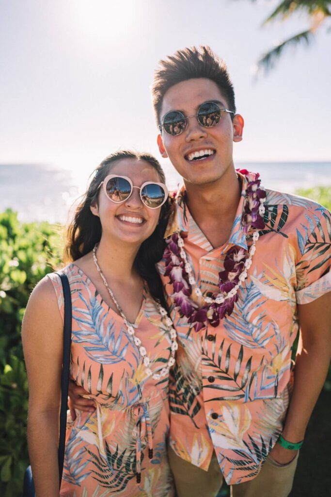 Image of a man and woman wearing matching Aloha shirts/dress and leis while they pose at a luau in Hawaii