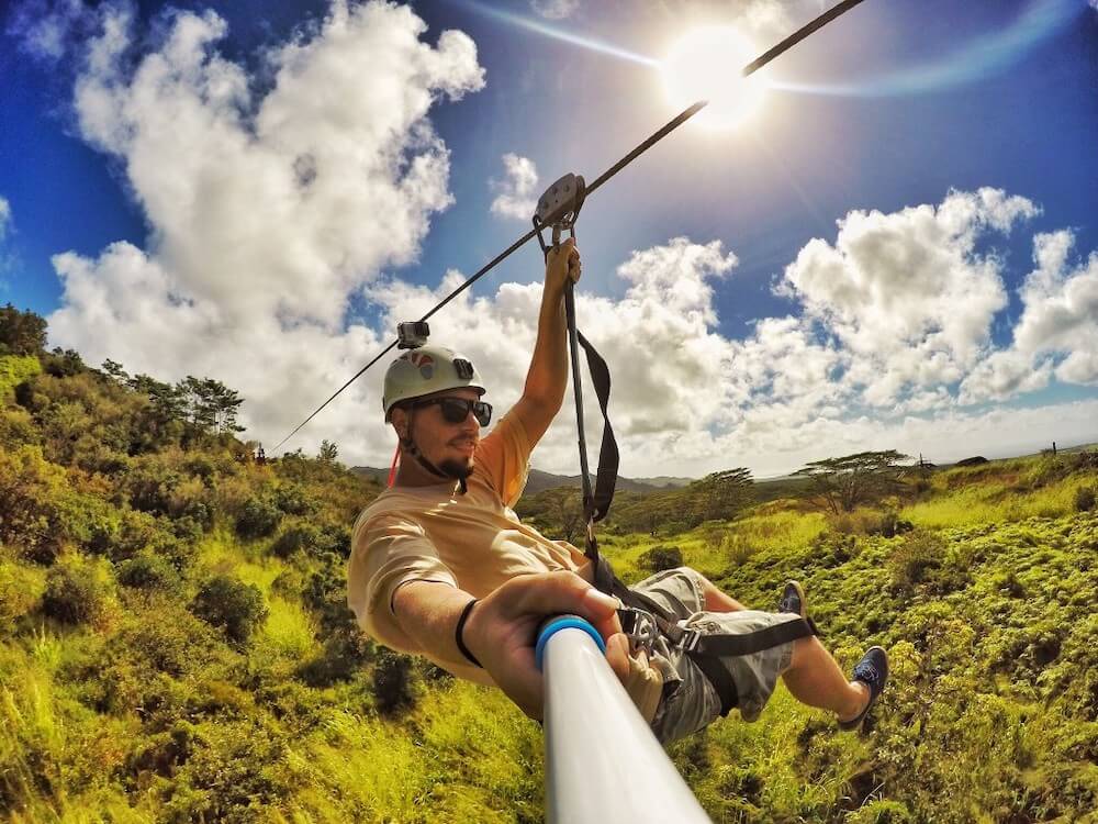 Image of a man ziplining in Hawaii while holding a selfie stick