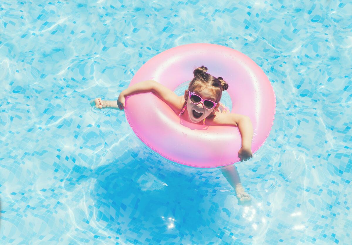 Find out the best Maui resorts for families recommended by top Hawaii blog Hawaii Travel Spot! Image of a girl in a pink inflatable ring in a swimming pool