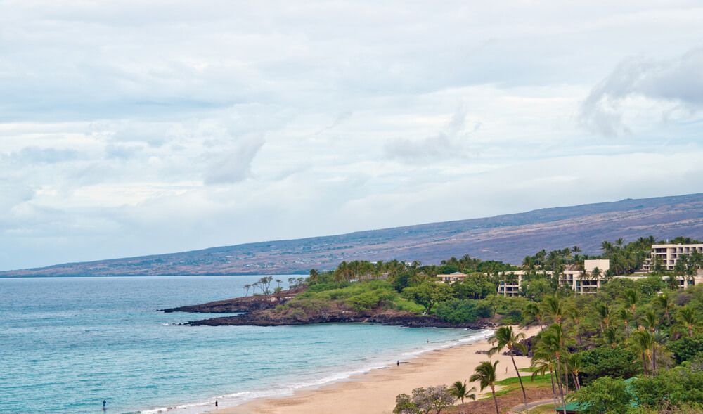 Hapuna Beach State Park on the Big Island. Image of a golden beach with green hills in the background.