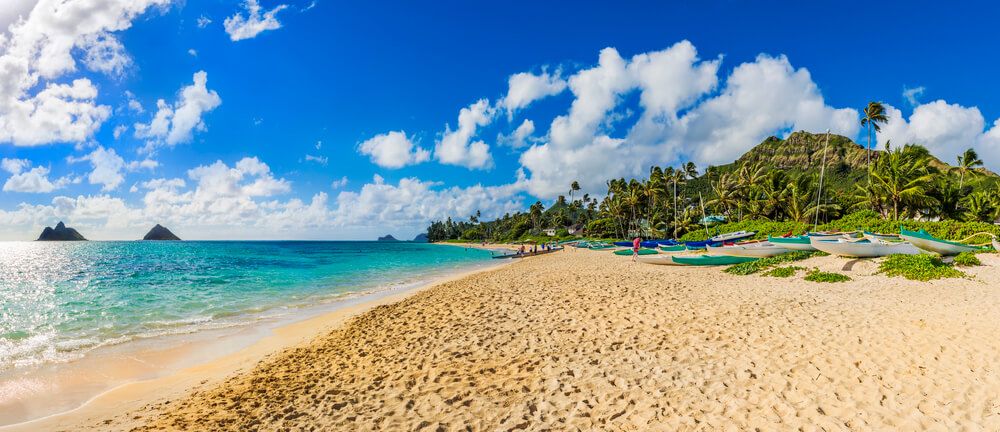 Image of a wide sandy beach with mountains and two islands in the background