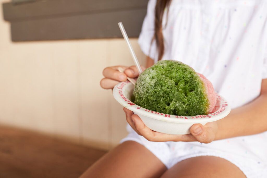 Matsumoto Shave Ice in Haleiwa. Image of a girl holding a green and pink shave ice in Hawaii.