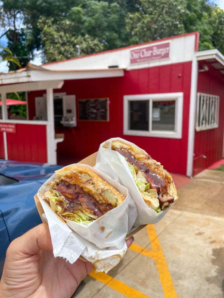 Best Burgers on Kauai: Image of a burger in front of the Duane's Ono-Char Burger on Kauai