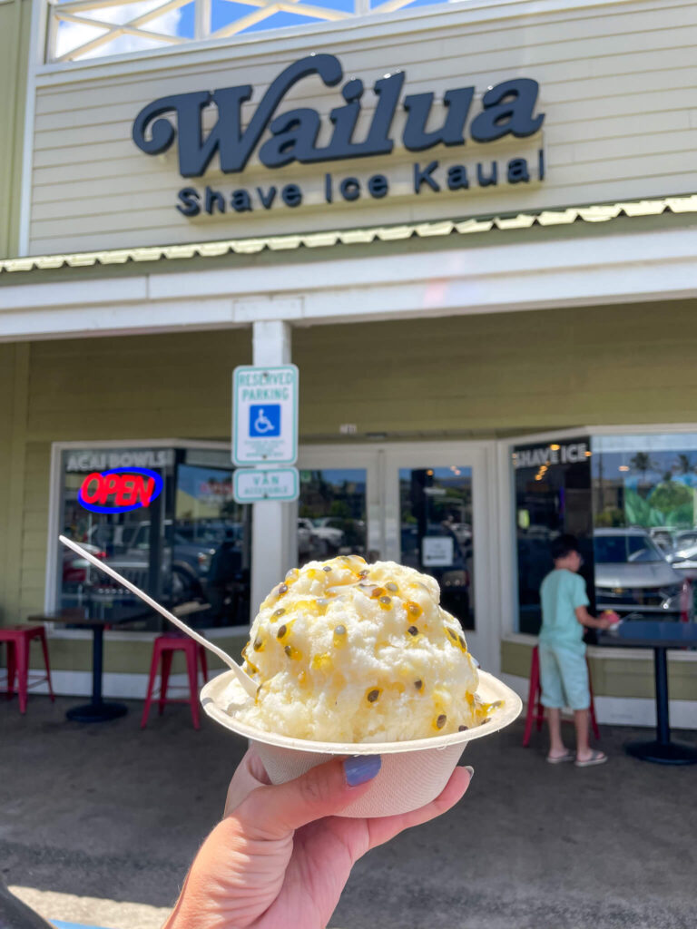 Image of someone holding a bowl of shave ice in front of the Wailua Shave Ice sign