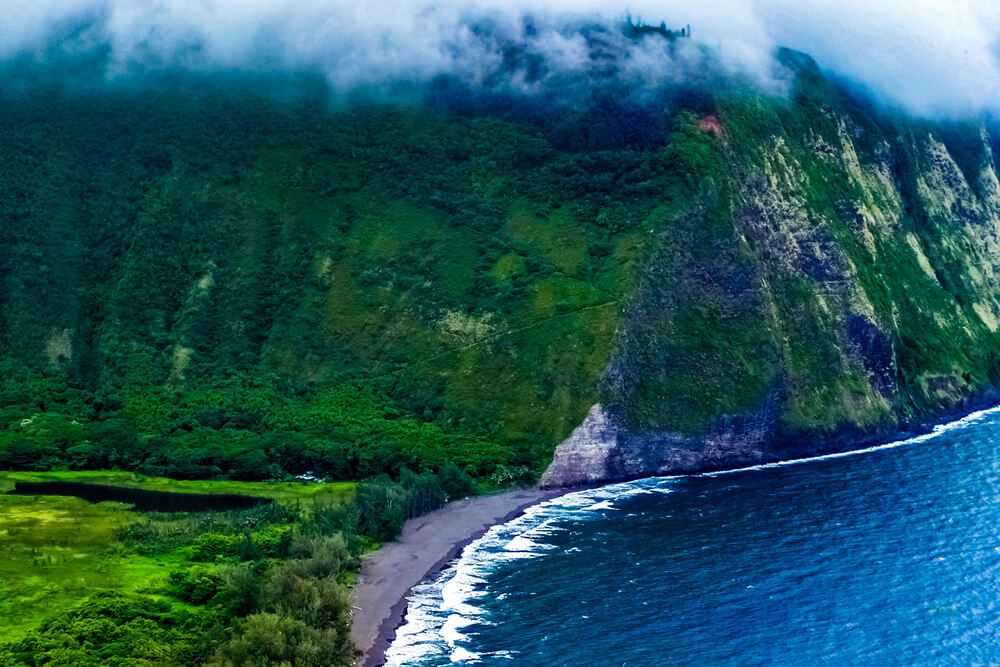 Waipo Valley Beach on the Big Island of Hawaii. Image of a black sand beach surrounded by green valley