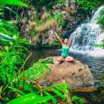 Find out the best Kauai waterfalls recommended by top Hawaii blog Hawaii Travel Spot! Image of a woman meditating in front of a waterfall on Kauai