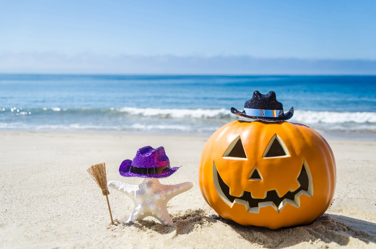 Find out how to celebrate Halloween in Hawaii by top Hawaii blog Hawaii Travel Spot! Image of a jack o lantern and starfish in Halloween attire on a beach
