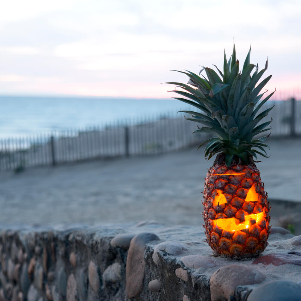 How to celebrate Halloween in Hawaii: Image of a jack o lantern pineapple on the beach