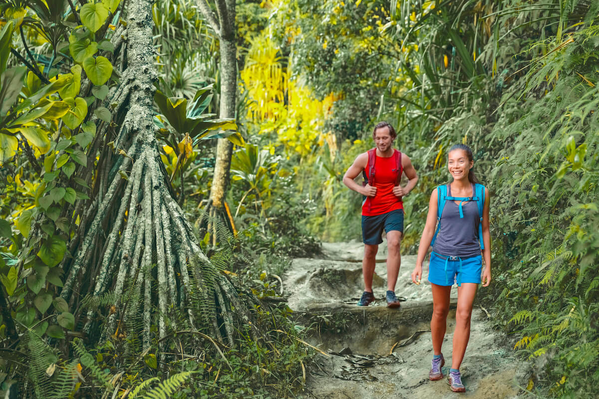 Check out this list of essentials for hiking in Hawaii recommended by top Hawaii blog Hawaii Travel Spot! Image of a man and woman hiking the Kalalau Trail on Kauai