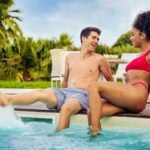 Check out the best honeymoon hotels in Maui recommended by top Hawaii blog Hawaii Travel Spot! Image of a couple sitting on the edge of a hotel pool in Maui