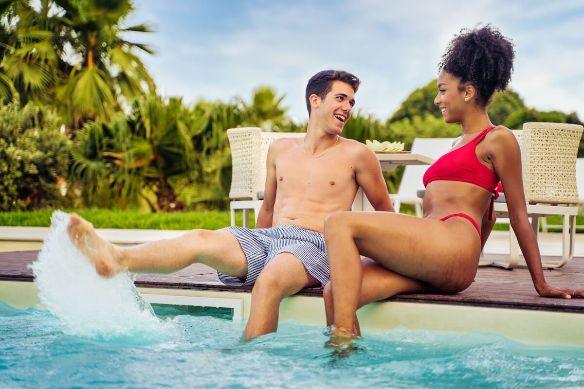 Check out the best honeymoon hotels in Maui recommended by top Hawaii blog Hawaii Travel Spot! Image of a couple sitting on the edge of a hotel pool in Maui