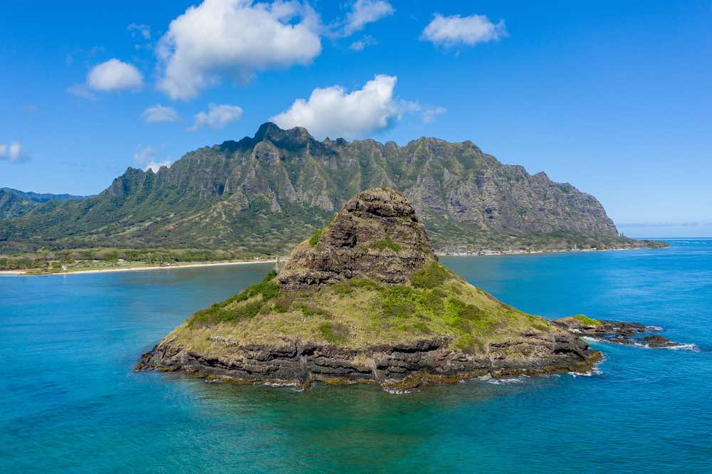 Aerial view of the Chinaman's hat with Kualoa beach and park with Ko'olau mountains in the background