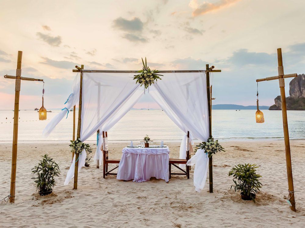 Image of a beach proposal set up with a tent, table, chairs, and lanterns