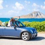 Check out this list of the best Hawaii quotes for Instagram captions recommended by top Hawaii blog Hawaii Travel Spot! Image of a couple taking a selfie in a convertible on Oahu