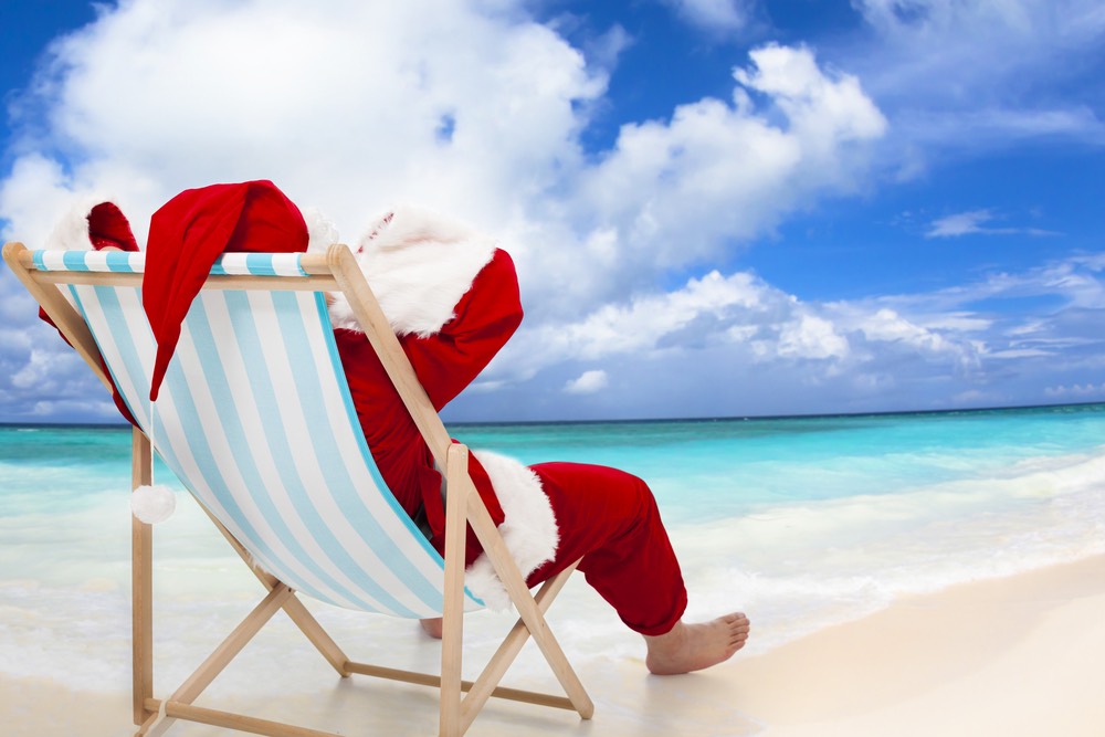 Santa Claus sitting on beach chairs with blue sky and cloud.Christmas Day concept.