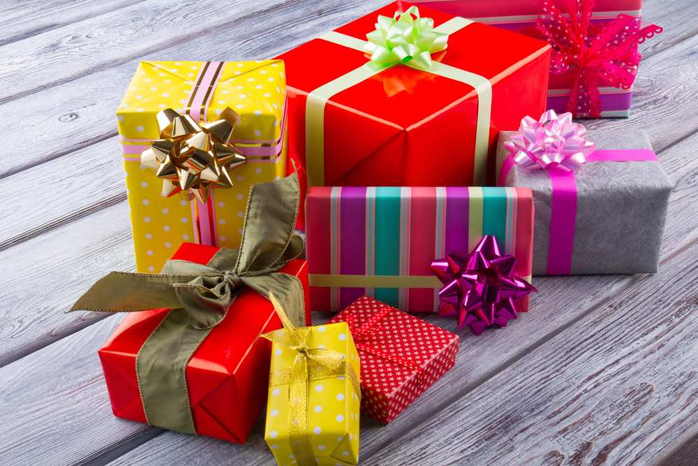 Should you pack Christmas presents for your trip to Hawaii? Image of Colorful gifts boxes. Heap of different gift boxes on wooden table. Christmas presents.