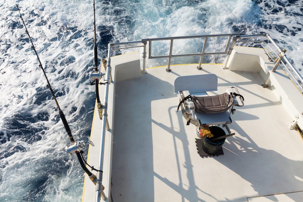 View from upper bridge of deep sea sport fishing boat with 2 lines set up and empty fish fighting chair. Offshore fishing in Hawaii.