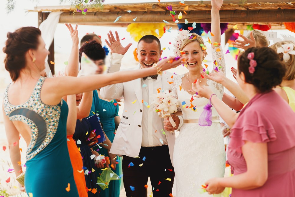 beautiful  gorgeous blonde bride  and stylish groom under confetti, hawaii  colorful sand ceremony